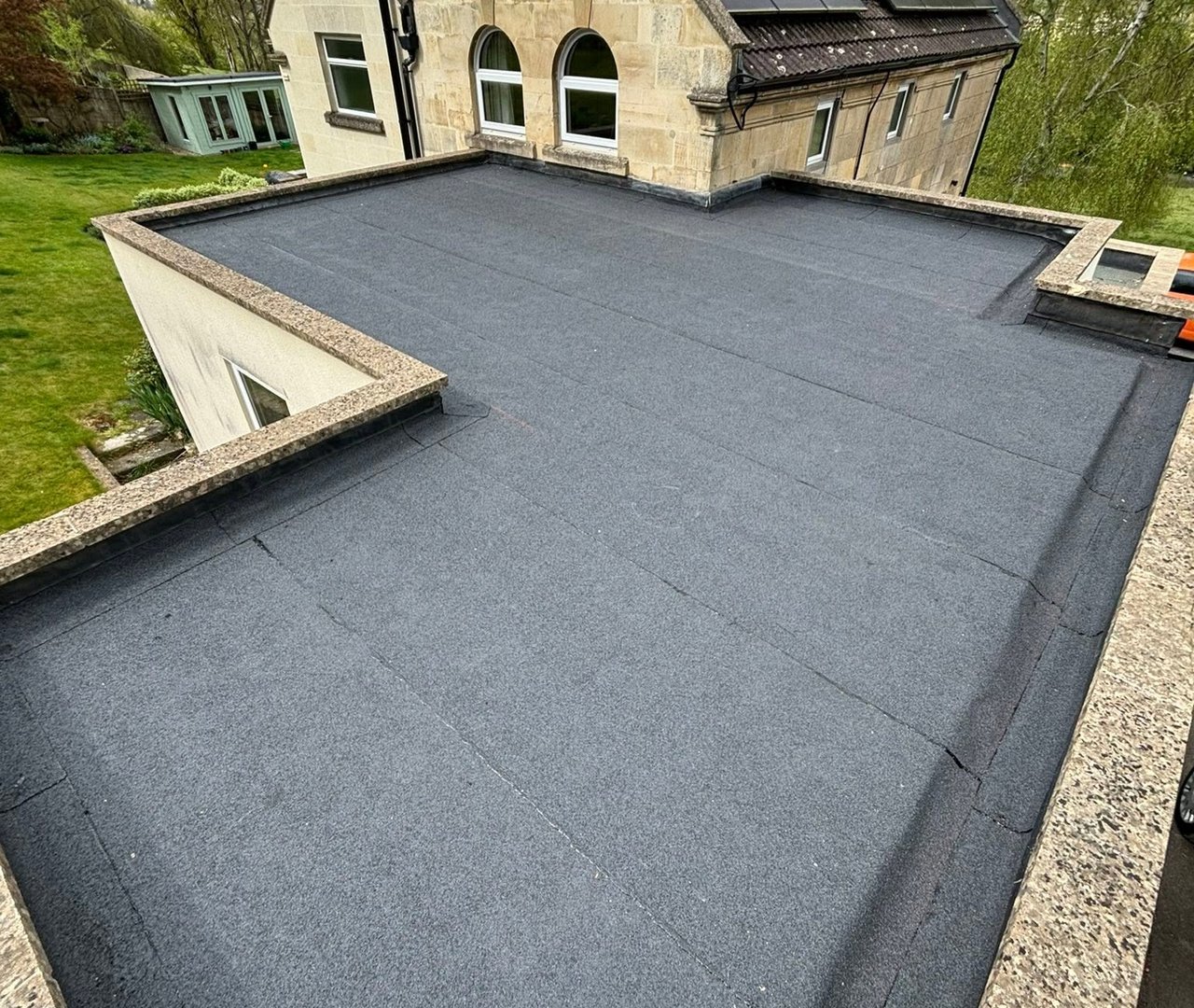 Completed flat roof beside a stone home